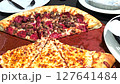 Delicious pizza featuring a combination of cheese and meat lovers toppings, served on a wooden board. The golden cheese stuffed crust and melting cheese emphasize fresh and irresistible flavors, creat 127641484