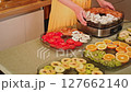 Housewife preparing a food dehydrator machine with various sliced fruits and vegetables 127662140