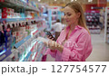 Customer using smartphone scanning products in supermarket hygiene aisle 127754577