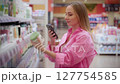 Customer using smartphone scanning product in supermarket 127754585