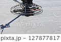 Construction worker operates power trowel to finish concrete slab at job site under works day 127877817