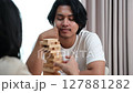 Two Asian teenage boys and girls playing wooden games at home during school break. 127881282