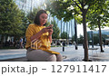 Businesswoman using smartphone in a modern park green trees, glass buildings 4k 127911417