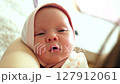 Newborn baby falling asleep in mothers arms and smiling in sleep, close up 127912061