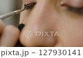Applying eyelashes. Extreme close-up video of makeup artist applies eyelashes to model eyelids using glue and tweezers 127930141