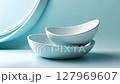 White ceramic bowls spin gently on a soft blue background, creating a calming and stylish visual 127969607