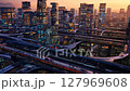 Futuristic city with illuminated skyscrapers and flying vehicles at sunset 127969608