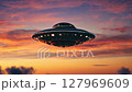 Unidentified flying object hovering in dramatic sunset sky 127969609