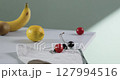 A cozy backdrop with fresh fruits and grass on a table with natural sunlight and shadows. 127994516