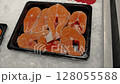 Fresh-looking pink salmon fillets neatly arranged in plastic tray. 128055588