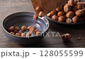 Homemade trail mix toasted hazelnuts cascading into bowl ready for snacking. 128055599
