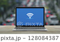 Wi-fi flat icon on modern laptop computer screen on wooden table over blur of rush hour with cars and road in city, Technology internet wireless concept 128084387