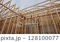 Workers are constructing wooden frame structure, complex arrangement of beams at construction zone 128100077