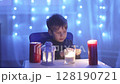 A boy sits at a table with candles 128190721