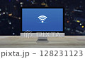 Wi-fi icon on desktop modern computer monitor screen on wooden table over blur colorful night light city tower and skyscraper, Technology communication concept 128231123