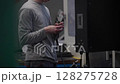 Close-up of a factory worker using a handheld rotary tool to fine-tune a metal component in an industrial setting. Concept of precision engineering, manual machining, skilled labor 128275728