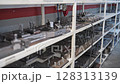 Metal parts and industrial machine components neatly arranged on shelves in a CNC workshop. Concept of tool storage, mechanical engineering, precision manufacturing, and industrial order 128313139
