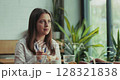 Two coworkers eating healthy lunch welcome cheerful female colleague joining them in slow motion 128321838