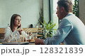 Two coworkers eating healthy lunch welcome cheerful female colleague joining them in slow motion 128321839