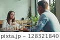 Two Caucasian coworkers eat healthy lunch and talk to each other in slow motion at the office cafeteria 128321840