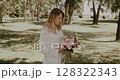 young beautiful woman holds bouquet of fresh flowers and enjoying 128322343