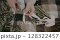 woman decorates bouquet as gift. Floristry creating flower 128322457