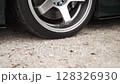 A CloseUp Image of a Car Wheel Positioned on a Textured Gravel Surface for Detailed Observation 128326930