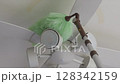 Cleaning a ceiling fan light with a duster Zoom in 128342159