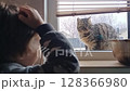 An Adorable and Curious Encounter Between a Child and a Charming Cat Seen Through a Window 128366980