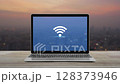 Wi-fi flat icon on modern laptop computer screen on wooden table over blur of cityscape on warm light sundown, Technology internet wireless concept 128373946