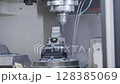 Close-up of a CNC machine during high-precision metal milling, with cooling fluid spraying and cutting tool in action. Concept of industrial automation, machining, and metal fabrication 128385069