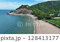 Ocean waves reaching calm sandy beach near rocky hill 128413177