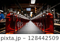 Bottled amber liquids line the production conveyor in a busy distillery during the afternoon hours 128442509