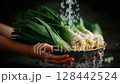 Fresh green onions being washed in a bowl under running water by hands in a kitchen 128442524