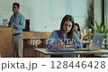 Female employee prepares pitch with laptop and notebook during lunch break in close up slow motion pan  128446428