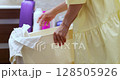 woman housekeeper takes dirty white clothes and liquid detergent into basket in bathroom, close-up 128505926