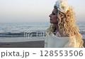 Peaceful blonde woman in white by the sea enjoying quiet sunset moment 128553506
