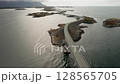 Winding path of Atlantic ocean road connects multitude of rocky islands across expansive sea. Cars traversing remarkable feat of engineering in Norway 128565705