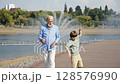 A Joyful Walk Between a Grandfather and His Grandson at the Beautiful Park Setting 128576990