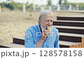 A senior man is happily enjoying a delicious ice cream outdoors, feeling joyful and content 128578158