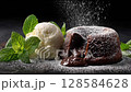 A decadent chocolate lava cake with rich molten center is paired with a scoop of vanilla ice cream and garnished with fresh mint leaves. Powdered sugar sprinkles complete this elegant dessert scene. 128584628