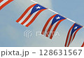 Colorful Puerto Rico flag bunting fluttering in the wind against a bright blue sky with soft clouds. Perfect for patriotic themes, cultural videos, festivals, and Caribbean travel content. 128631567