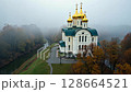 Orthodox church with golden domes on a foggy autumn day. 128664521