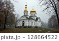 Orthodox church with golden domes on a foggy autumn day. 128664522