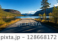 scenic mountain road leading to a lake autumn foliage bright sunny day 128668172