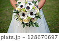 Bride holding wedding Bouquet with anemones and greenery. 128670697