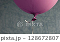 Bottom part of pink balloon with rubber tail tied with long string on blurred background. Magenta color helium balloon rise up and floating in air 128672807