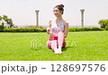 A healthy woman hydrating after yoga on natural grass under the blue sky 128697576