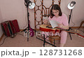 Guitarist with classical guitar methodically selects notes and studies them. Woman musician then positions notes on music stand before commencing practice session in domestic music studio. Handheld 128731268