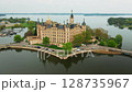 Camera pulls away from Schwerin Castle, revealing stunning lakes and lush gardens around this fairytale palace in Germany. Perfect shot for travel or history themes.  128735967